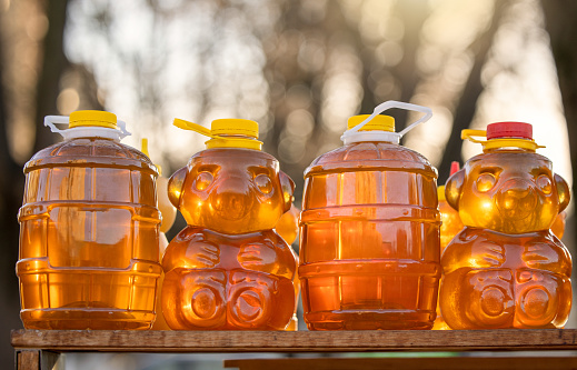 Golden sweet honey in plastic bottle in grocery market outdoor