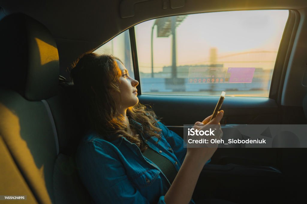 Woman in taxi in Dubai at sunset Young Caucasian woman with smartphone on backseat of taxi in Dubai at sunset Car Stock Photo