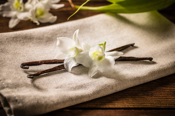 vainas de vainilla y flores en una mesa de madera - vainilla fotografías e imágenes de stock