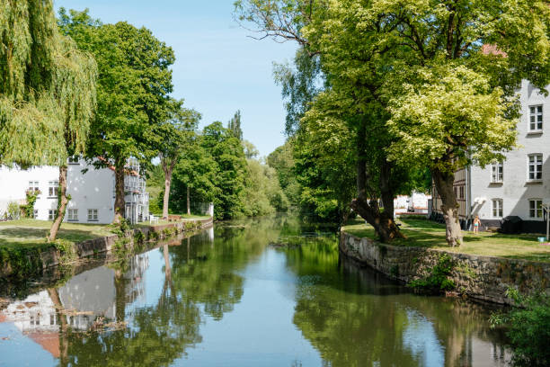 istock Canal surrounded by greenery and buildings on a sunny day 1455434596