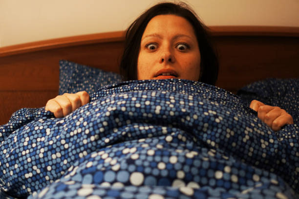 istock Caucasian female in bed looking at something scared 1455436496