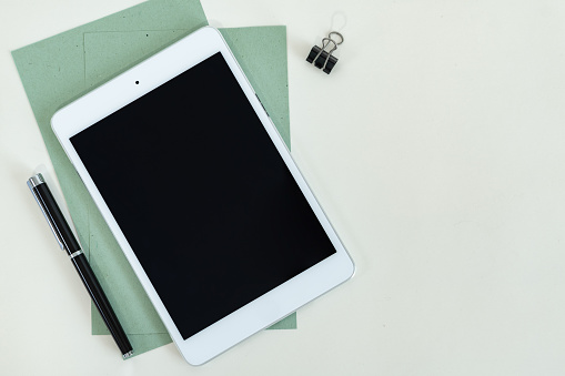 A tablet and pen on green and white background with a copy space