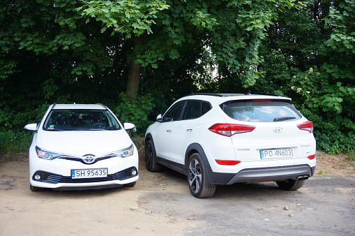 Poznan, Poland – May 27, 2018: Two white Honda and Toyota cars parked near a forest in Poznan, Poland