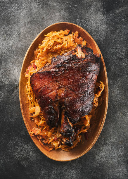 schweinshaxe, in german cuisine, is a roasted ham hock (or pork knuckle). smoked pork ham hock, pork knee served with sauerkraut. - shank sauerkraut german cuisine pork imagens e fotografias de stock