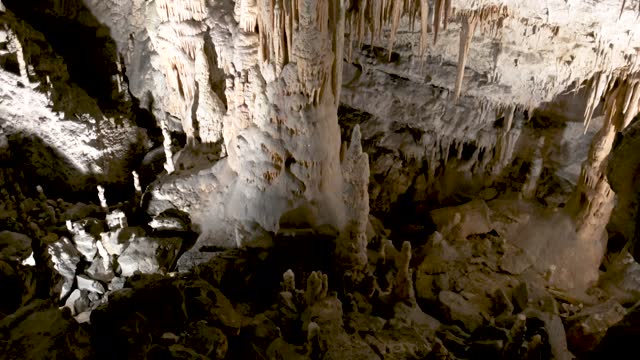 Postojna caves interior pan over stalagmites stalactites. Riding through an illuminated tunnel, part of a cave system in Postojna in Slovenia