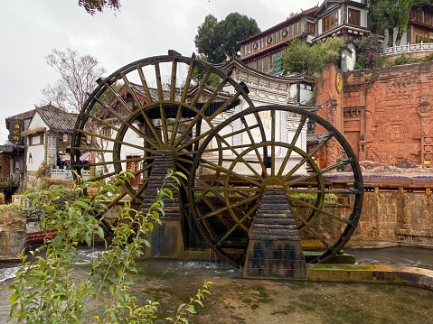 A rusting water wheel with a building in the background