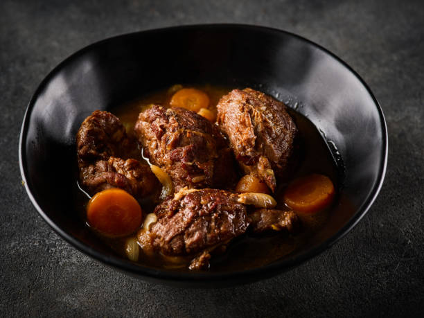 bochechas de porco estufadas com legumes, sobre um fundo cinzento. comida espanhola ou alemã - pork chop fine dining wine - fotografias e filmes do acervo