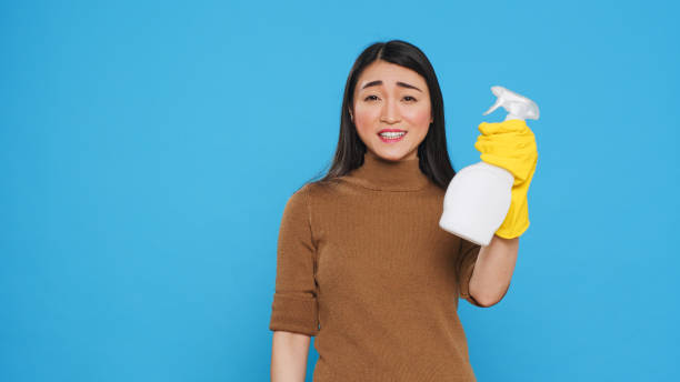 istock Asian housekepper pointing and showing hygiene products 1455441849