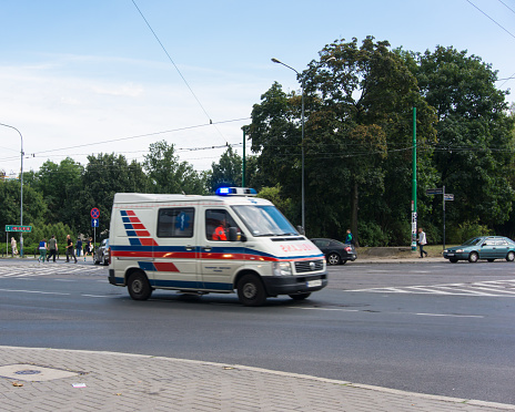 Poznan, Poland – August 28, 2013: Ambulance with lights driving an intersection in the center of Poznan, Poland