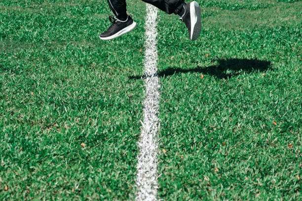 サッカー場でジャンプして走る人 - soccer field grass single line lawn ストックフォトと画像