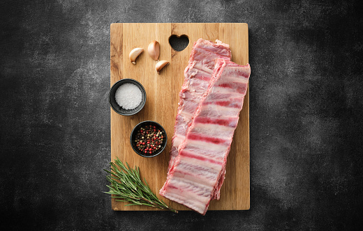 Raw pork ribs with spices, salt, pepper and rosemary. Fresh pork. Pig ribs