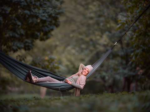 Young happy woman relaxing in hammock during autumn day in nature. Copy space. Photographed in medium format.