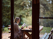 Relaxed woman reading a book in autumn day on a patio.