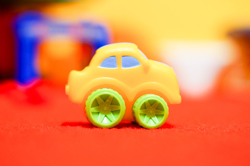 A selective focus shot of a plastic toy car on red carpet