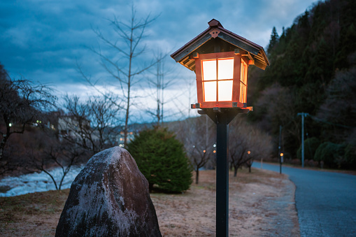Traditional Asian-style lanterns shaped like red houses provide a warm glow by the side of the cold winter evening. The location is in a park in Aichi, Japan.