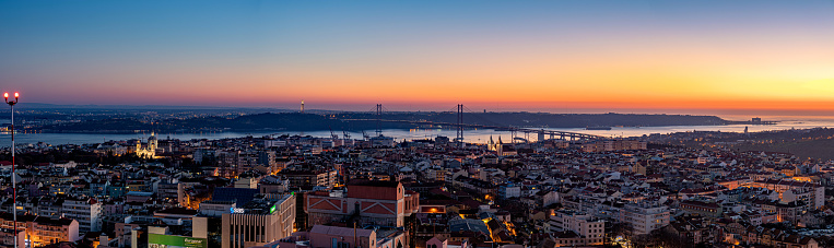 A panoramic shot of a mesmerizing sunset over Lisbon with illuminated buildings