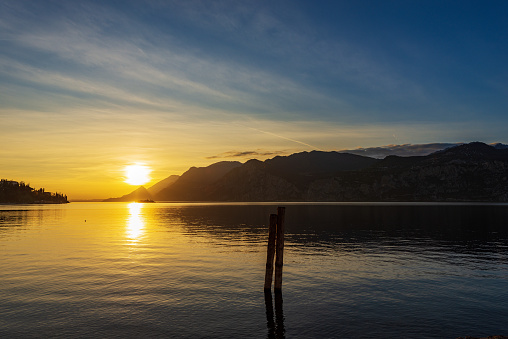 Beautiful sunset on Lake Garda (Lago di Garda) view from the small village of Malcesine, Verona province, Italy, Veneto, southern Europe. On background the coast of Lombardy with the Alps.