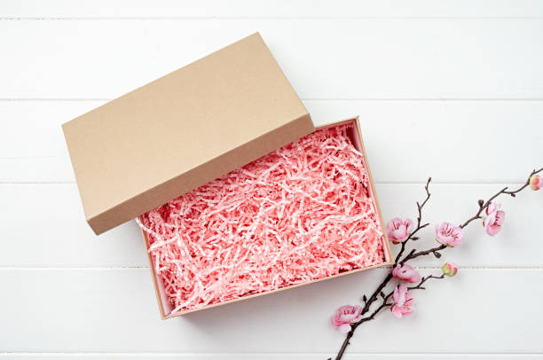 istock Shredded pink paper packing material texture in a craft box with sakura branch, mockup design 1455449627