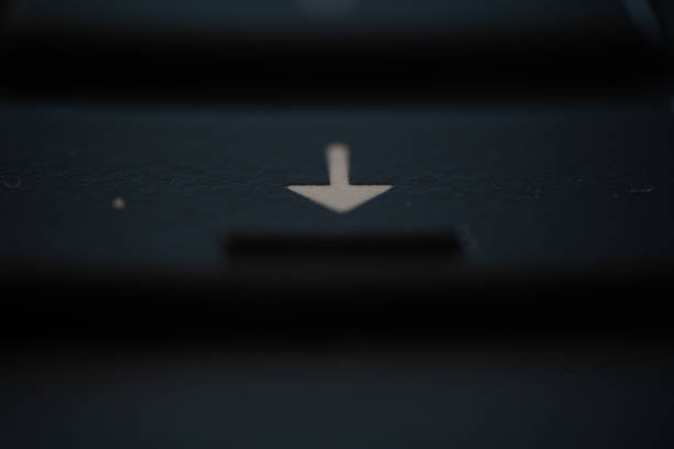 A closeup shot of an arrow down sign on a dark surface