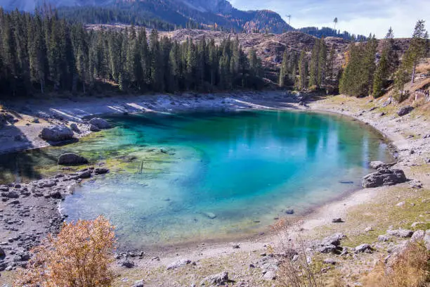 The idyllic tourist hotspot and must see Lago di Carezza in the Dolomites. A deep blue mountain lake surrounded by trees.