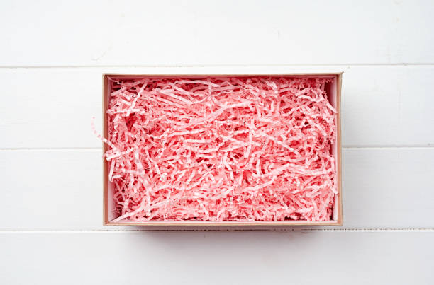 istock Shredded pink paper packing material texture in a craft box, mockup design 1455451034