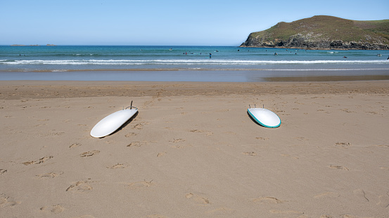A shot of surf boards on a beach in the background of a wavy sea.