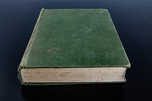 A closeup of a book with a green cover on a blue background