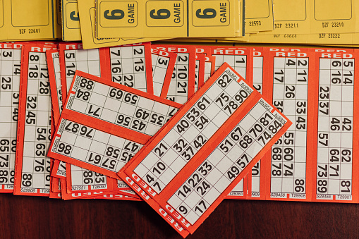Bingo tickets on a wooden table indoors in Newcastle upon Tyne, England. There are different numbers on the cards, ready to be called by the bingo caller and marked off by the players.