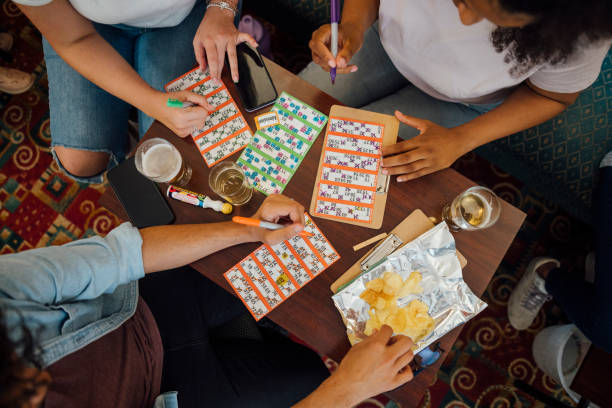 Line or House A group of people sitting in a social club enjoying an alcoholic drink while playing a game of bingo together in Newcastle upon Tyne, England. They are all marking numbers off their bingo cards. bingo equipment stock pictures, royalty-free photos & images