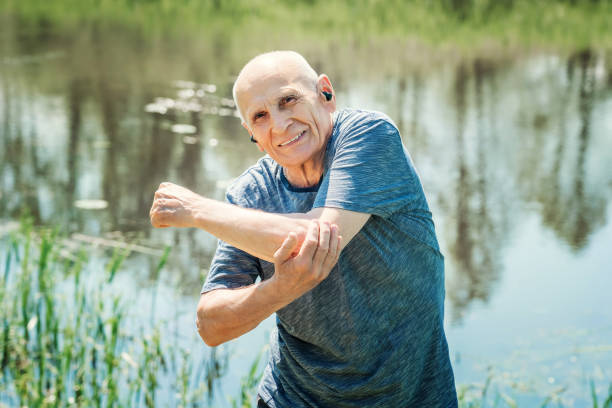 istock Older man in earphones doing stretching exercises on nature 1455457554