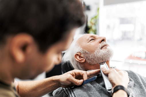 Senior man at barber getting his beard trimmed