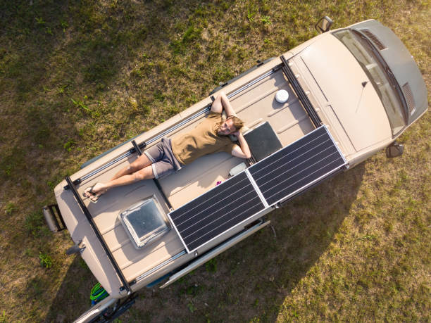 Aerial view of a man lying on the roof of a camper van stock photo