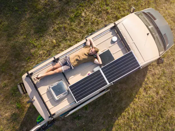 Top down view of a man relaxing on top of a DIY build camper van.