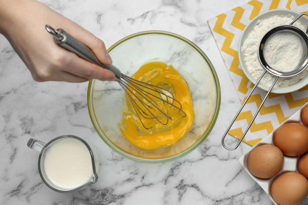 istock Woman whisking eggs at white marble table, top view 1455460780