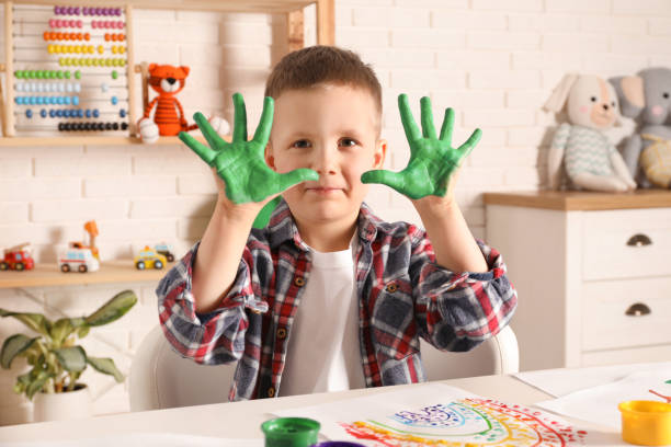 istock Little boy showing painted palms at white table indoors 1455461746