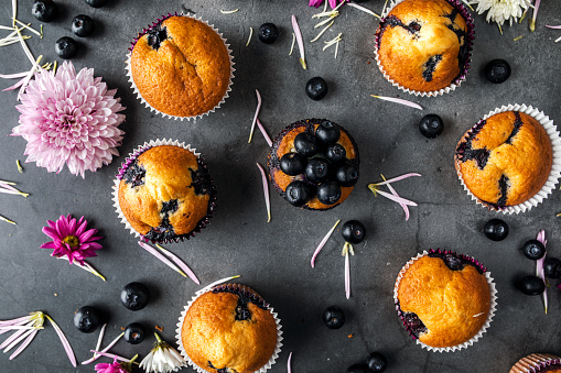 Homemade blueberry muffins  and flowers on a black background