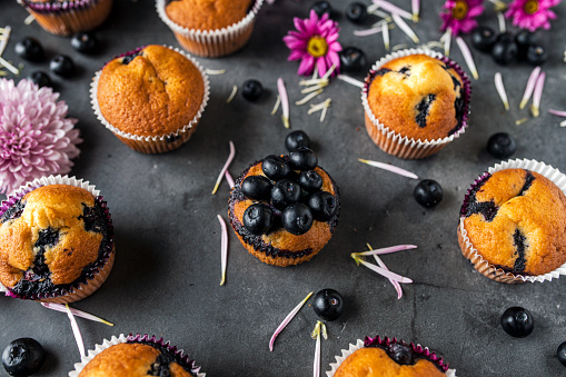 Homemade blueberry muffins  and flowers on a black background