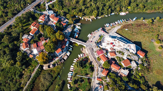 Aerial drone view of Montenegro. Small town with river with a bridge over it, a lot of greenery, buildings and moored boats