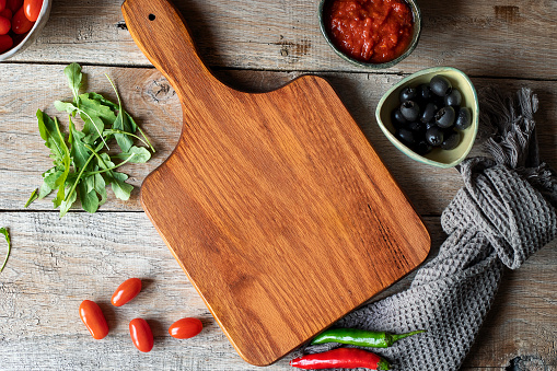 Empty handmade rustic wooden gray cutting board, with a fresh vegetables for vegan or vegetarian food preparation, on a rustic wooden table, table top view with a large copy space