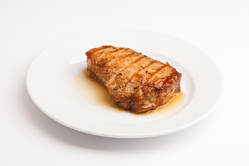 A beautiful photo of a closeup menu of fresh tasty steak on a plate on a white background