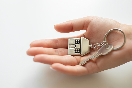 Woman giving metallic key with house shaped key chain to lodge