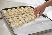 Woman hand holding cookie doughs to lined up on a baking sheet
