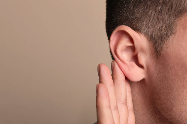 istock Man showing hand to ear gesture on beige background, closeup. Space for text 1455467836
