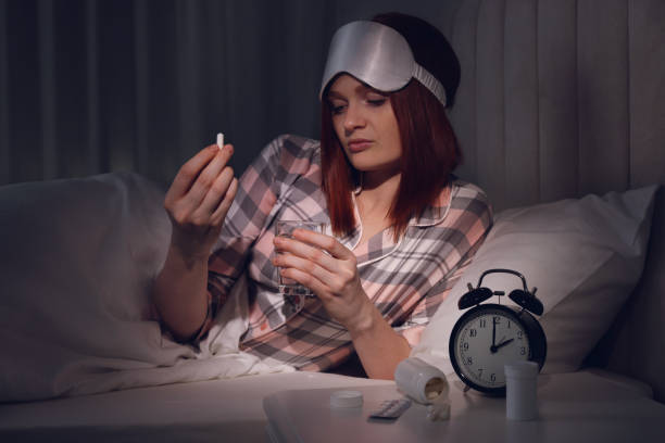 Woman suffering from insomnia taking pill in bed at night Woman suffering from insomnia taking pill in bed at night sleeping pill stock pictures, royalty-free photos & images