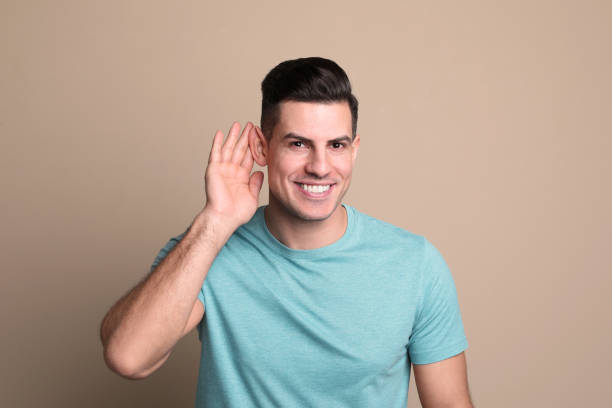 istock Man showing hand to ear gesture on beige background 1455468322