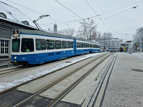 Zurich Enge Railway Sttaion. The first Building was opened in 1875, the new building was realized between 1925 and 1927. The station building is constructed of granite from the Ticino.\nThe image shows the Railway Station during winter season with a Tram Nr.5.