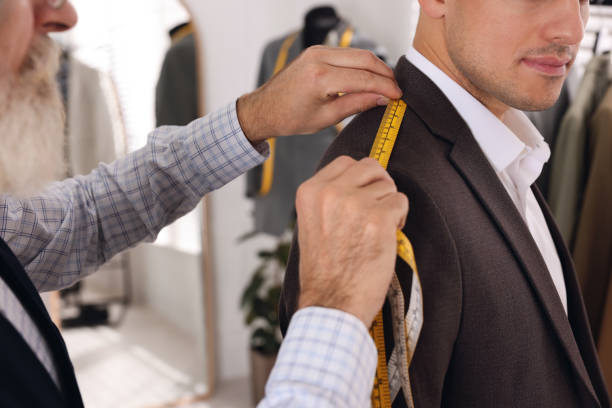 istock Professional tailor measuring shoulder seam length on client's jacket in atelier, closeup 1455471577