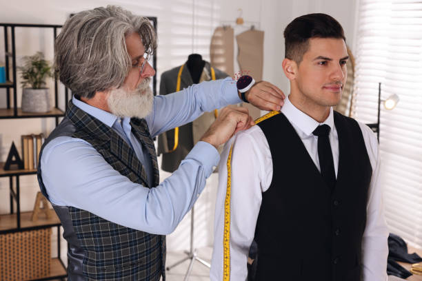 istock Professional tailor measuring shoulder seam length on client's vest in atelier 1455471627