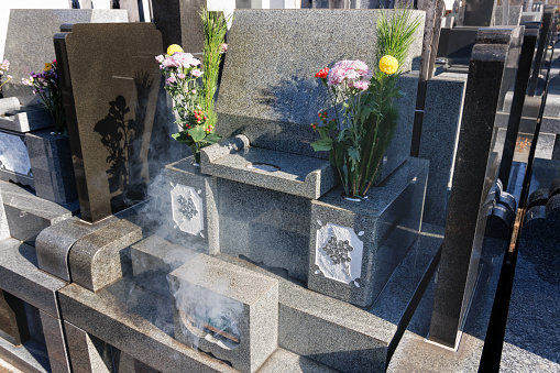 Incense sticks and flowers offered at the grave