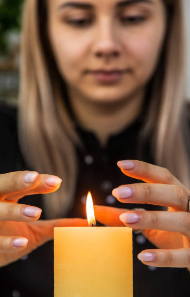 istock Woman fortune teller fortune telling on a candle. Selective focus. 1455473255